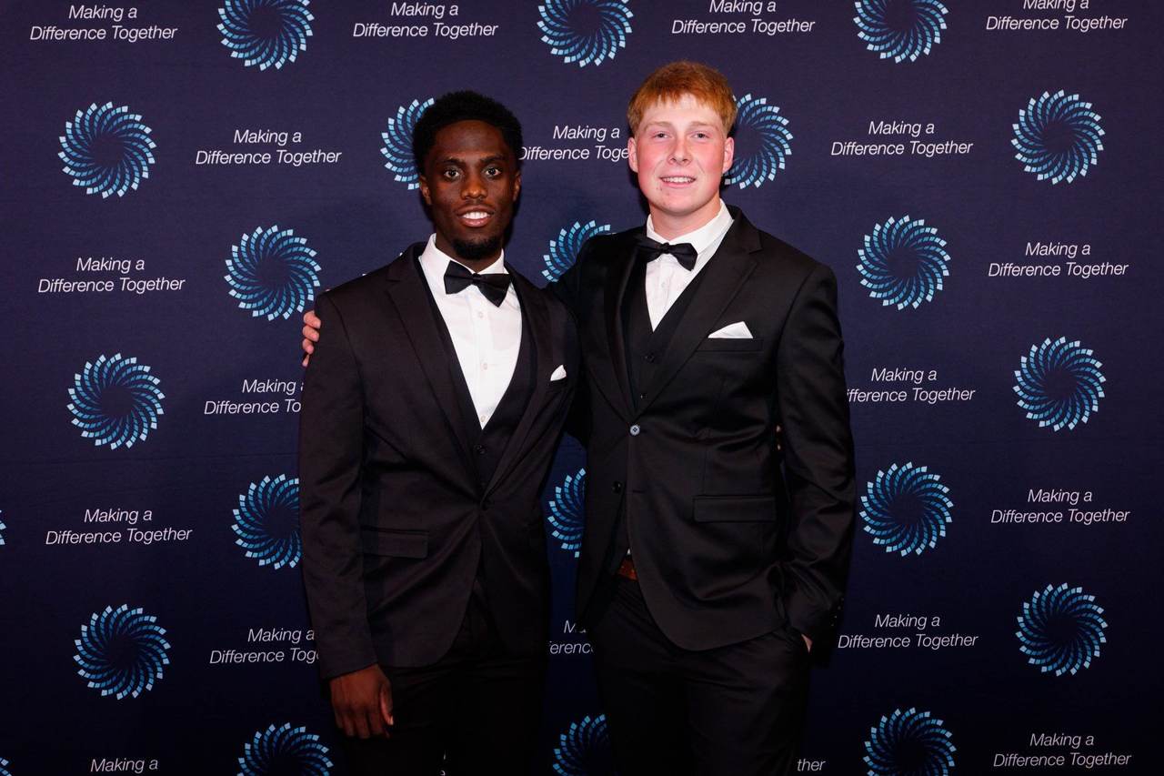 Two team members in tuxedos on the red carpet