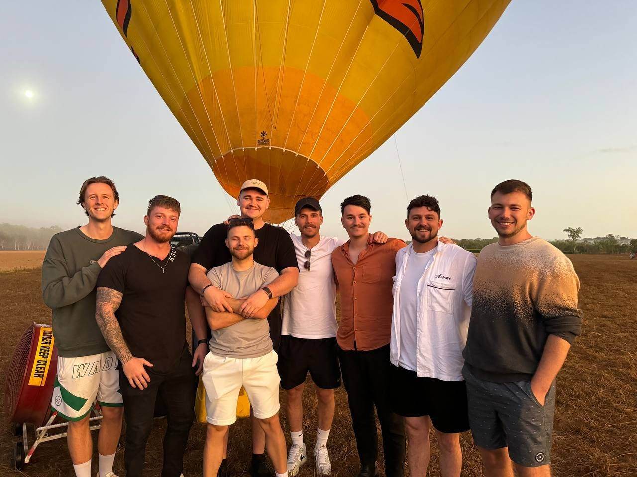 Team lined up in front of a hot air balloon at dawn
