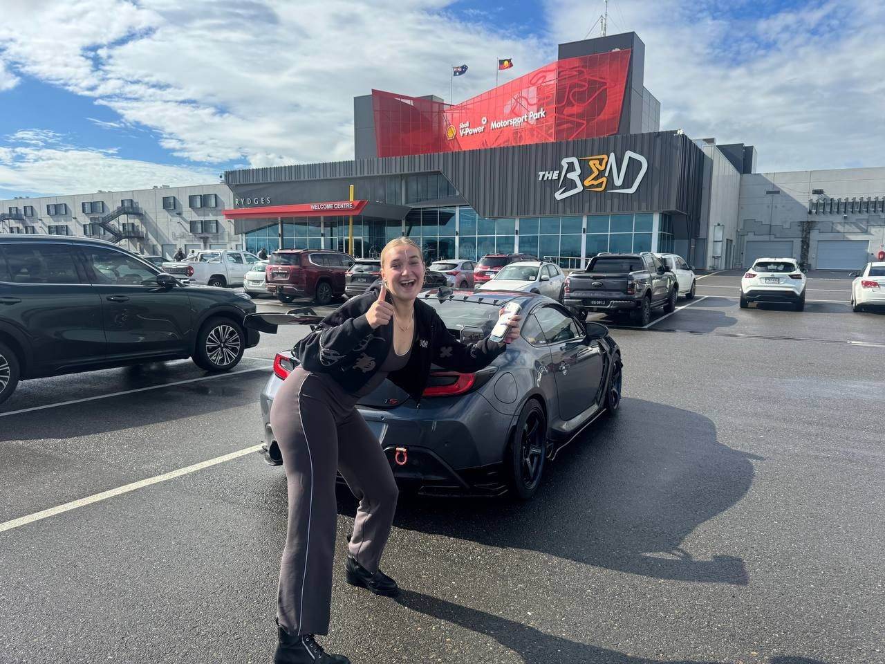 Team member celebrating beside a sports car at The Bend