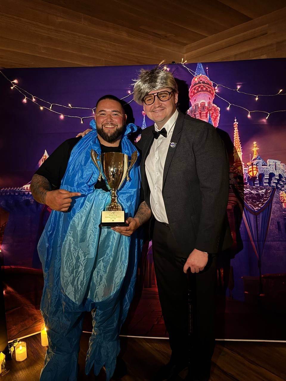 Two team members in costume holding a trophy