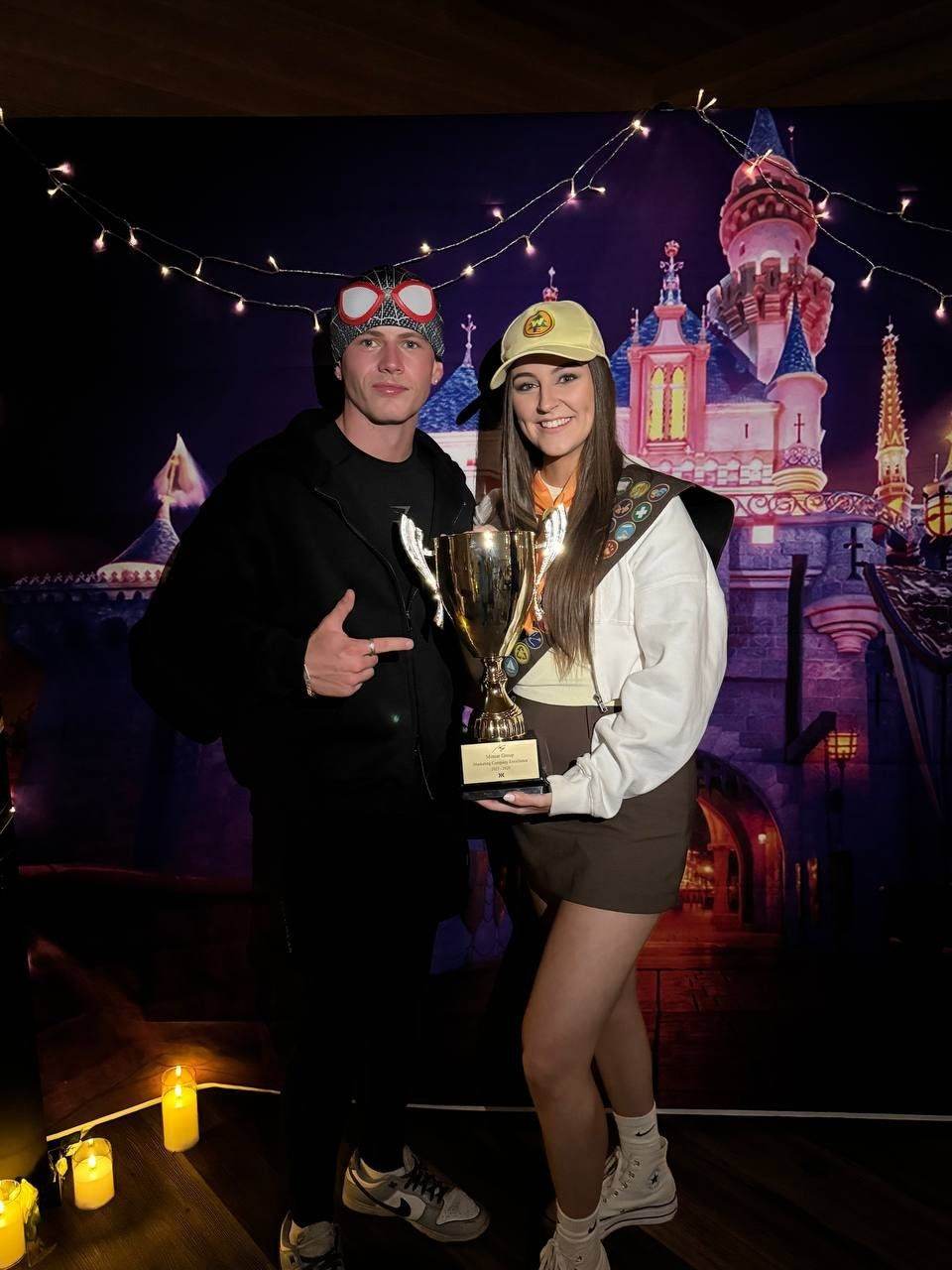 Two team members in costume with a trophy