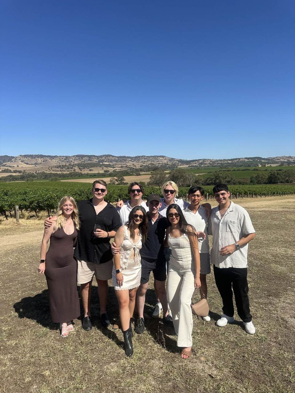 Team members standing among the vineyards